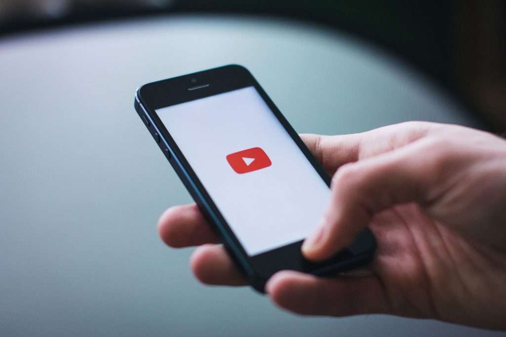 Hand holding a smartphone with the YouTube app open